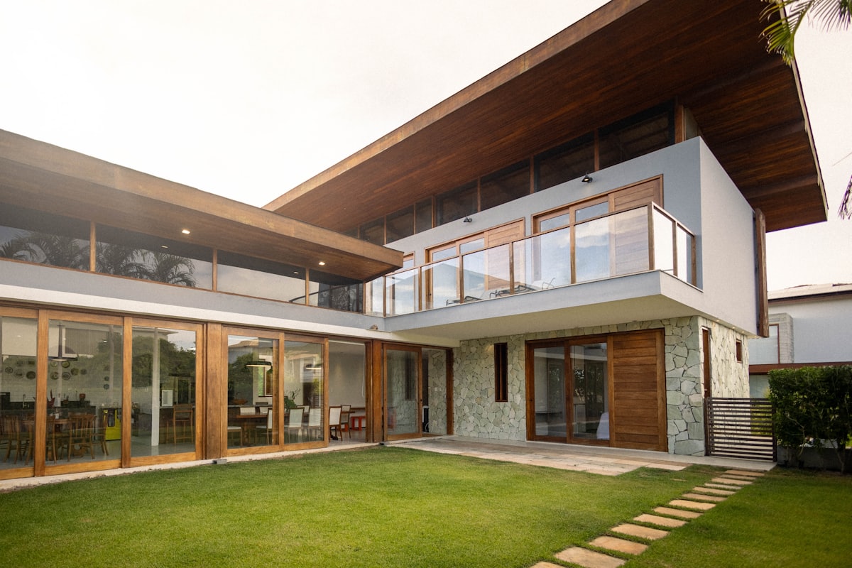 A two-storey home with stacked sliding doors and glazed balustrades opening onto a lawn