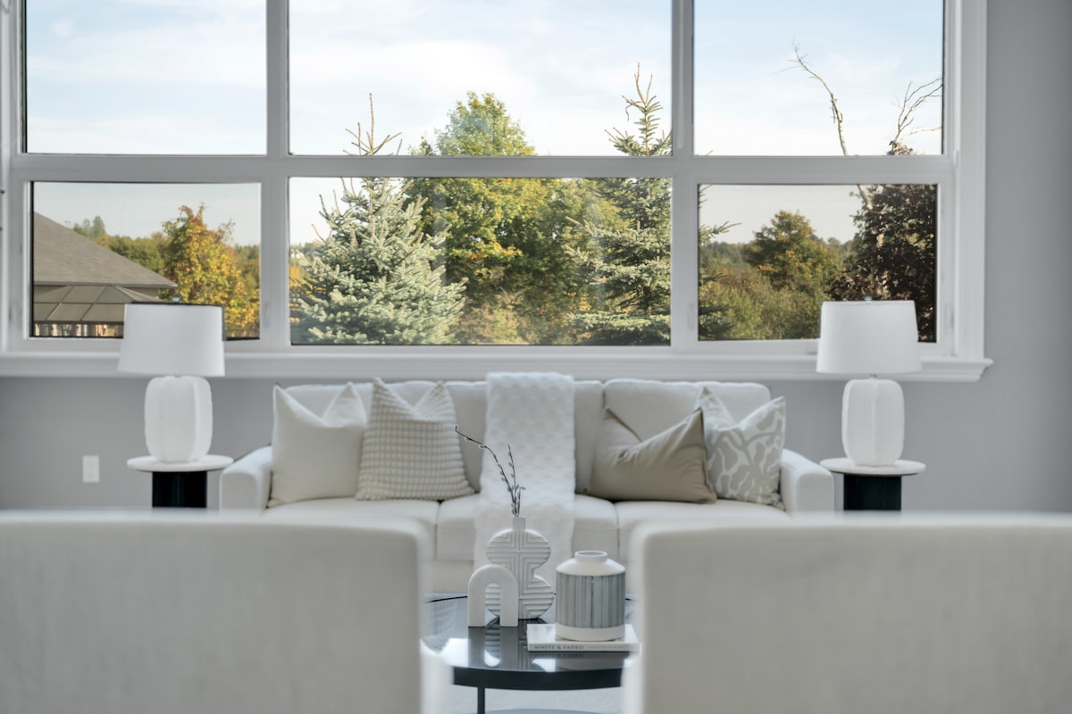 A bright living room with a wide multi-panel window looking onto trees