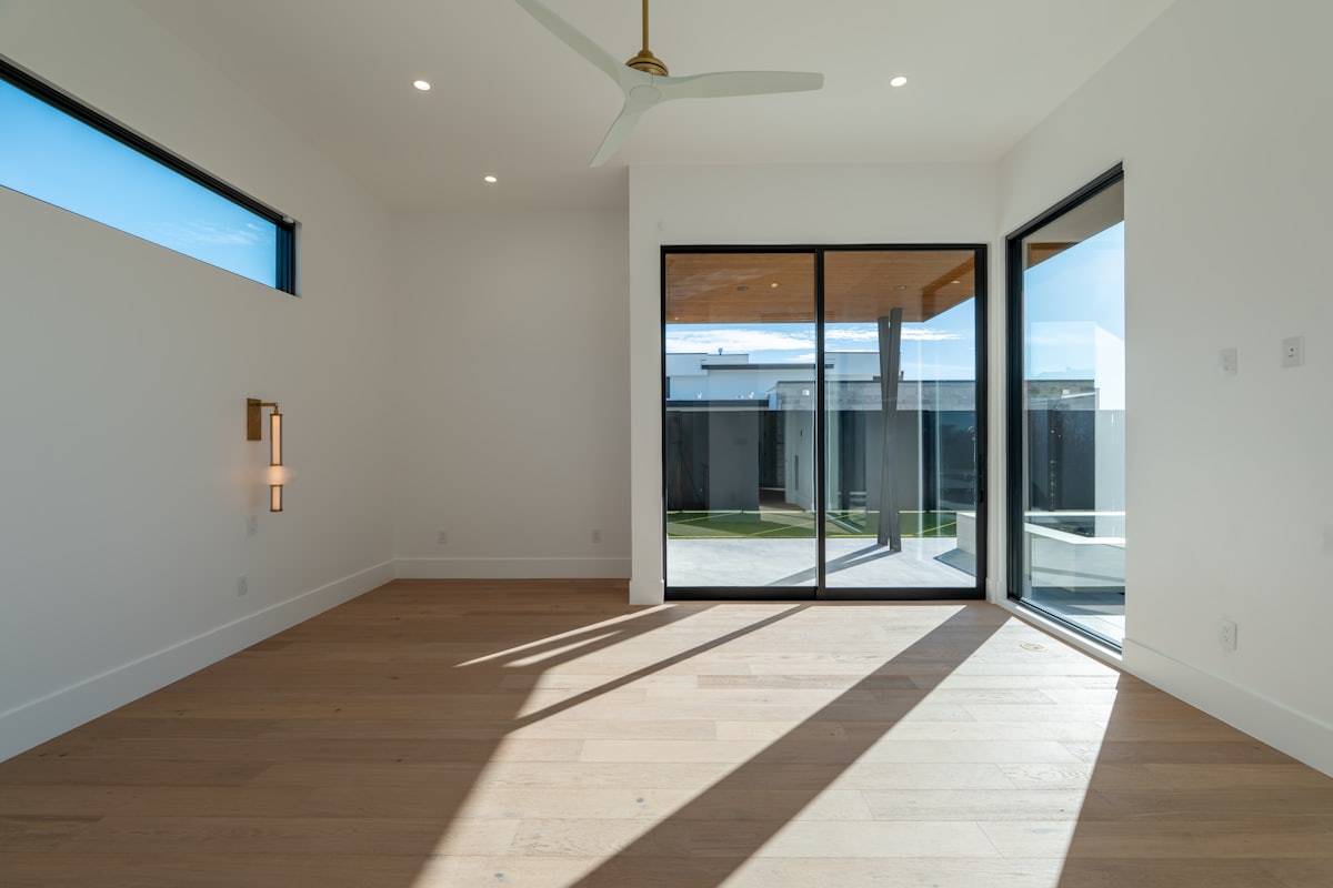 Black-framed sliding glass doors opening from a living space onto a courtyard